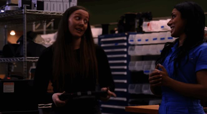 操作员坐在控制台前,面前摆放着Steam Deck设备以及连接线缆,身后则是正在运行中的机器人模型