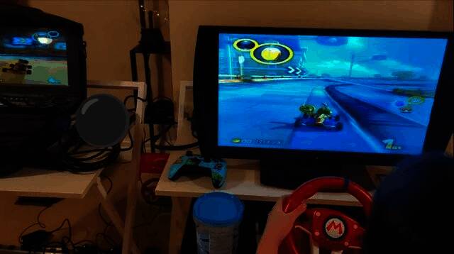 街机设备侧面展示，可以看到踏板与方向盘的联动结构