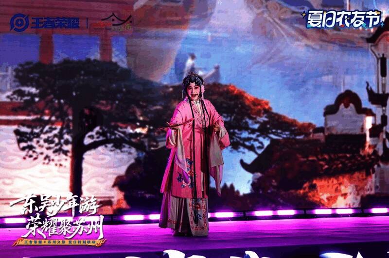 王者荣耀coser与苏州本地表演者在昆曲舞台上互动,背景为王者主题灯光装饰的金鸡湖夜景