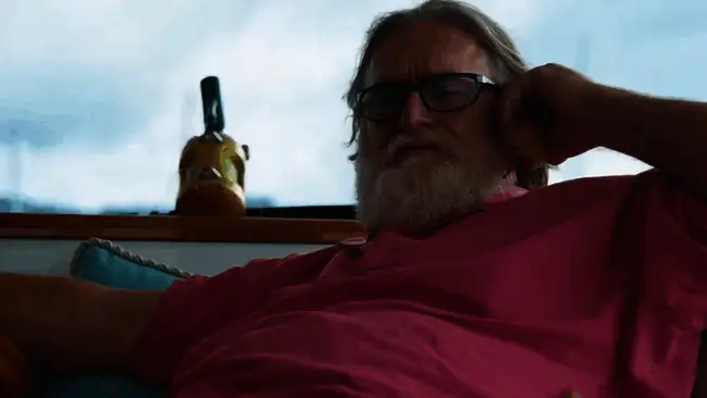 Gabe Newell在采访中认真阐述观点的特写画面,背景可见电脑屏幕显示着技术图表