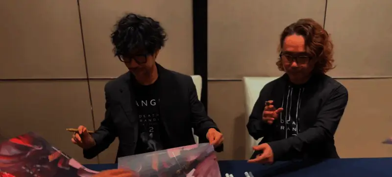 小岛秀夫在舞台上鞠躬致谢,背景大屏显示《死亡搁浅2》LOGO