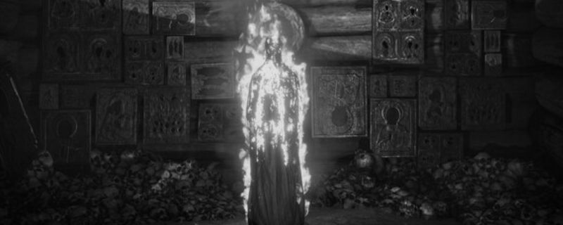 《独眼利霍》游戏主视觉图,灰暗色调下一位黑衣老妇轮廓浮现于森林深处,氛围阴森诡异