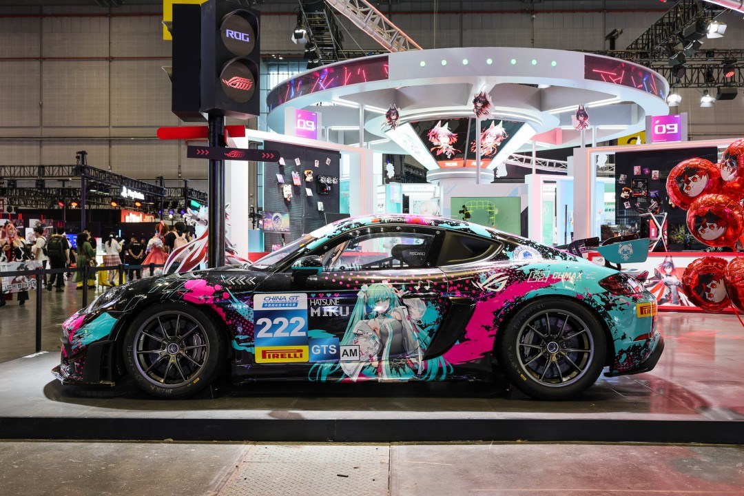 Tony大叔将ROG夜神5080纯金版显卡模型递给小岛，小岛饶有兴致端详，显卡表面金光闪耀