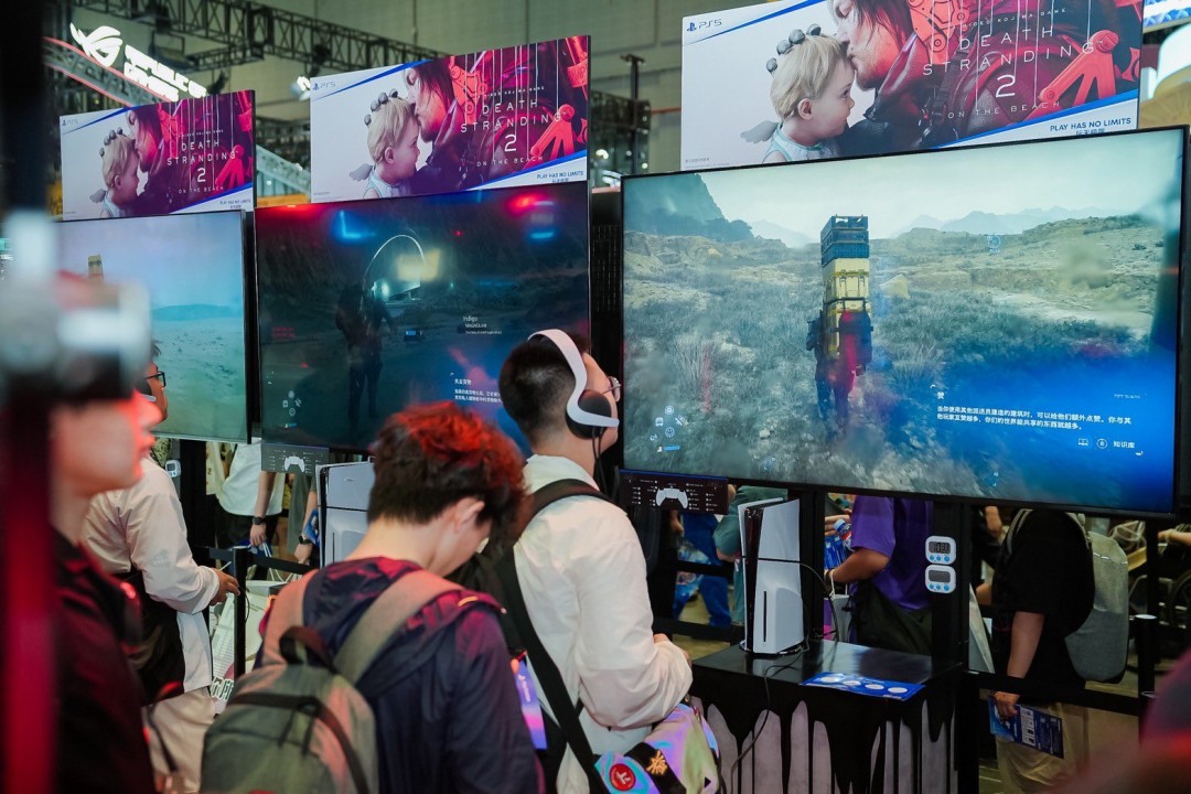 BW2025闭幕式合影墙：小岛秀夫居中，左右分别为曹真与徐慧，身后数十位中国本地化团队代表共同举手比‘∞’手势，象征连接无界