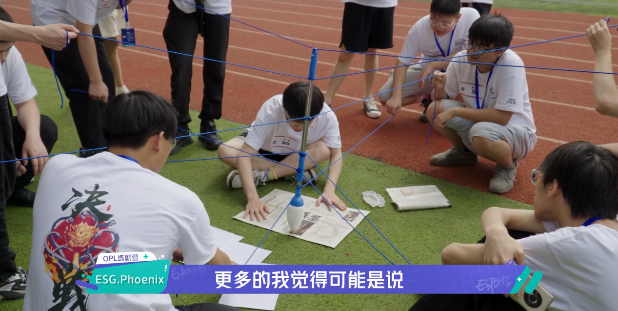 ‘神笔马良’活动现场特写：六名选手紧握彩色牵引绳，共同操控悬吊毛笔，在巨大白纸上稳稳写出‘OPL’三个英文字母，墨迹饱满，众人笑容灿烂