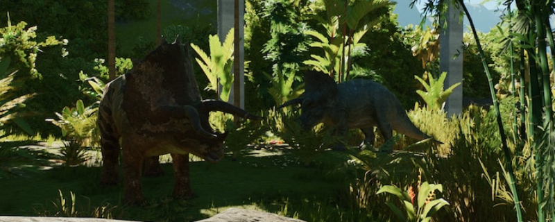 《侏罗纪世界:进化3》游戏内鸟脚类恐龙群居场景:数只色彩柔和的鸭嘴龙状生物在阳光斑驳的蕨类丛林中缓步进食,背景可见木质观景台与远处喷泉
