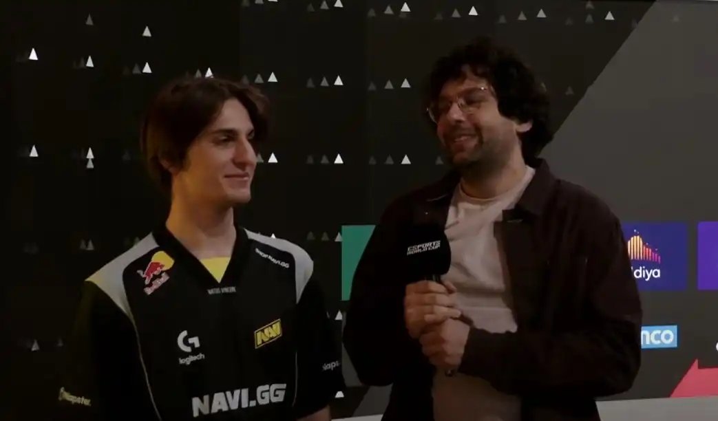 赛后采访现场图:NAVI队员围坐接受媒体提问,Riddys手持麦克风神情沉稳,身后电子屏显示‘NAVI 2-0 XG’战绩